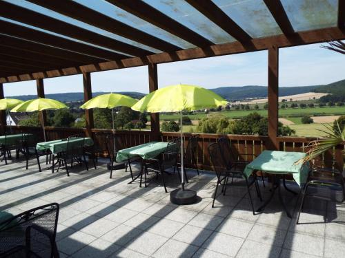 a patio with tables and chairs and yellow umbrellas at Hotel garni Zum Reinhardswald in Gewissenruh