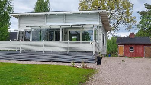 una casa con un portico coperto e un fienile rosso di Seeblickferienhaus a Lahti