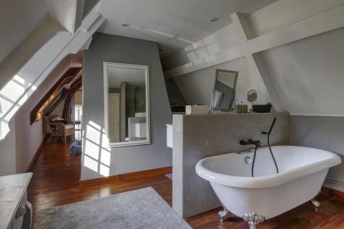 a bathroom with a white bath tub in a attic at Maison de Suzon in Saint-Pierre-le-Viger