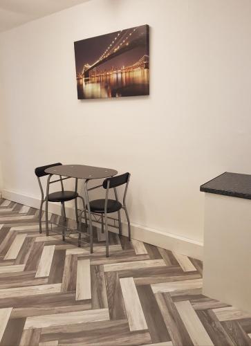 a dining room with a table and chairs on a wooden floor at Malvern Hotel in Sandown
