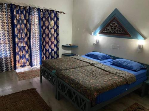 a bedroom with a bed with blue pillows and curtains at Neela House in Kovalam