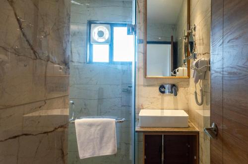 a bathroom with a sink and a shower at Pathikashram Nilaya in Gandhinagar