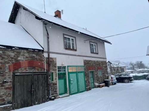 a brick building with green doors in the snow at Apartmány Kanteho grunt in Bělá pod Pradědem