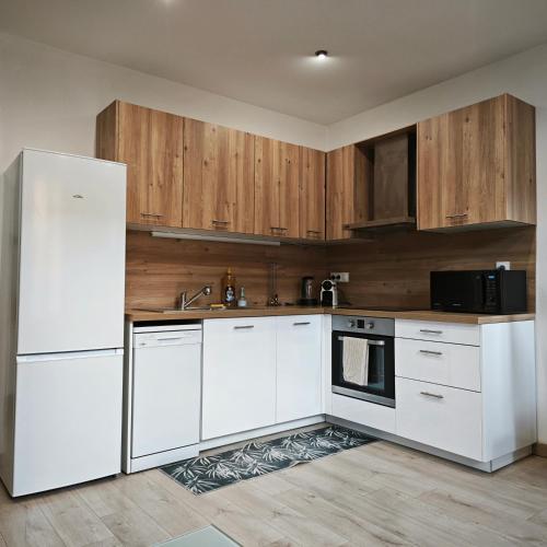 une cuisine avec des appareils électroménagers blancs et des armoires en bois dans l'établissement Appartement tout confort à 2 pas du centre ville, à Aubagne