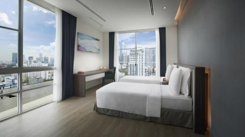 a bedroom with a large white bed and large windows at Shama Sukhumvit Bangkok in Bangkok