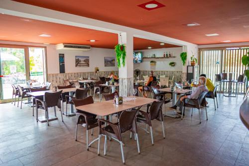 restauracja ze stołami i krzesłami oraz ludzie siedzący przy nich w obiekcie Camping Relax Sol w mieście Torredembarra
