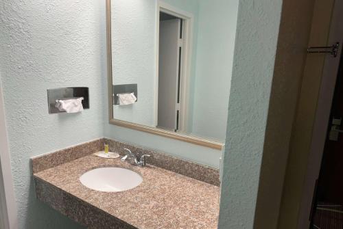 a bathroom with a sink and a mirror at Travelodge by Wyndham Airport Platte City in Platte City