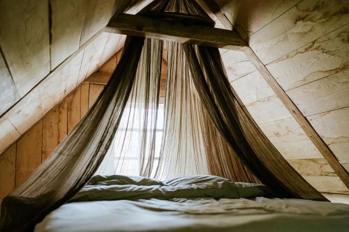 - une chambre avec un lit à baldaquin et une fenêtre dans l'établissement Les cabanes de roquehort, à Salies-de-Béarn