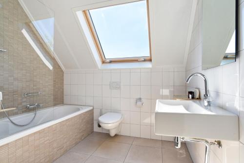 a bathroom with a sink toilet and a skylight at Dormio Strand Resort Nieuwvliet-Bad in Nieuwvliet