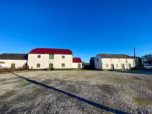 an old white barn with a red roof on a field at The Roadshed Apartments @ Rohans Farm in Midleton