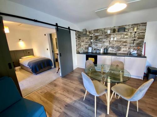 una habitación con mesa de cristal y sillas y un dormitorio en The Roadshed Apartments @ Rohans Farm, en Midleton
