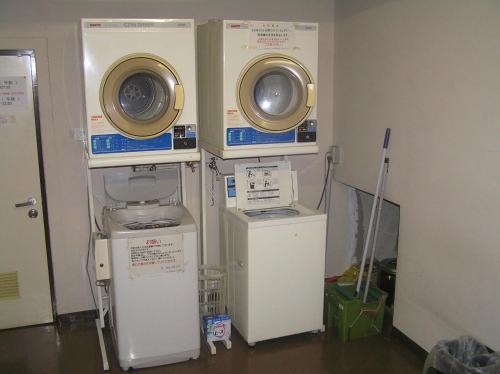 a room with two washing machines on the wall at Pension Young House in Furano
