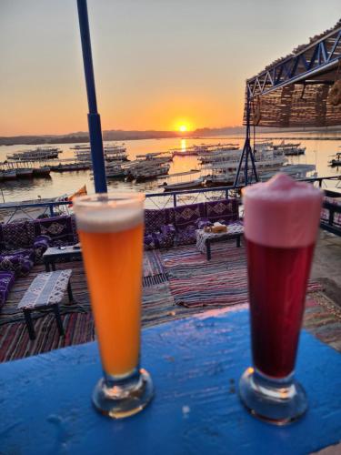 two drinks on a table with the sunset in the background at Endo Mando in Shellal