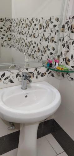 La salle de bains est pourvue d'un lavabo blanc et d'un rideau de douche. dans l'établissement Hotel Pratap Regal,Bharatpur, à Bharatpur
