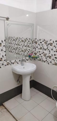La salle de bains blanche est pourvue d'un lavabo et d'un miroir. dans l'établissement Hotel Pratap Regal,Bharatpur, à Bharatpur