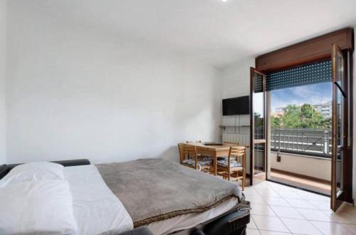 1 dormitorio con cama, escritorio y balcón en Bilocale condominio Trifoglio, en Gallarate
