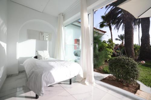 a white bedroom with a bed and a large window at Sun Club Playa del Ingles in Playa del Ingles