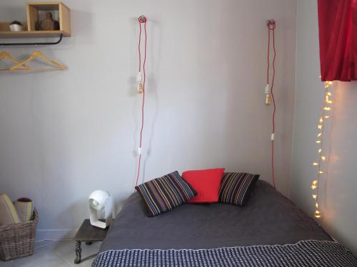 um quarto com uma cama com uma almofada vermelha e luzes em Studio avec cour extérieure em Bagnolet