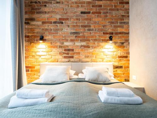 een slaapkamer met een bakstenen muur en een bed met kussens bij Mint Apartments Gdańsk DOKI in Gdańsk