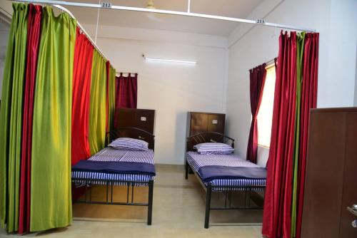 2 letti in una camera con tende rosse e verdi di Tranquil AC Comfortable stay for Male onlly a Bhubaneshwar