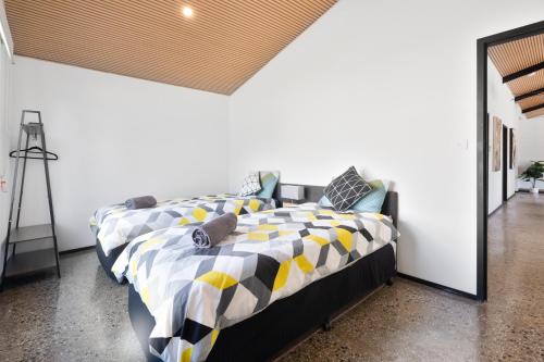 a bedroom with a bed with a yellow and black comforter at Shed House Lux Farm Stay in Buninyong
