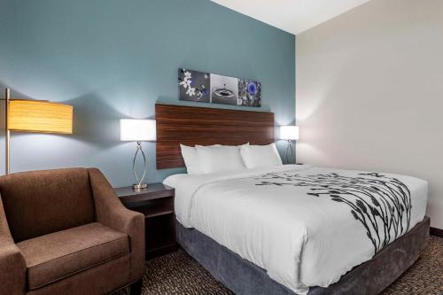 a hotel room with a bed and a chair at Sleep Inn & Suites Milwaukee-Franklin in Franklin