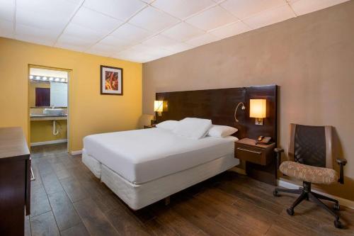 een slaapkamer met een wit bed, een bureau en een stoel bij Econo Lodge Gretna - New Orleans in Gretna