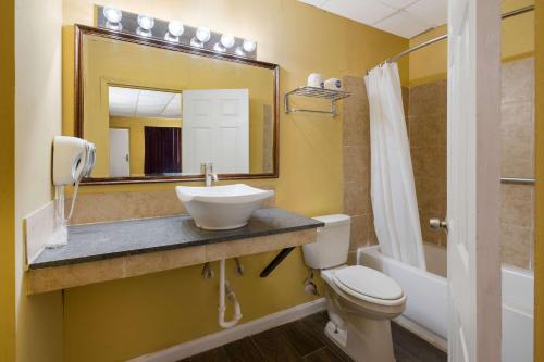 een badkamer met een wastafel, een toilet en een spiegel bij Econo Lodge Gretna - New Orleans in Gretna