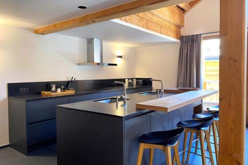 eine Küche mit blauen Schränken und einer Theke mit Stühlen in der Unterkunft CASA-Le Cherk Chalet 300m2 jacuzzi sauna Vars les Claux in Vars