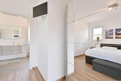 a white bedroom with a bed and a glass wall at Villa Meereszeit in Trent