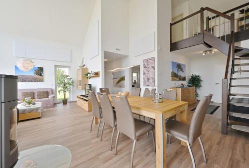 a dining room and living room with a wooden table and chairs at Villa Meereszeit in Trent