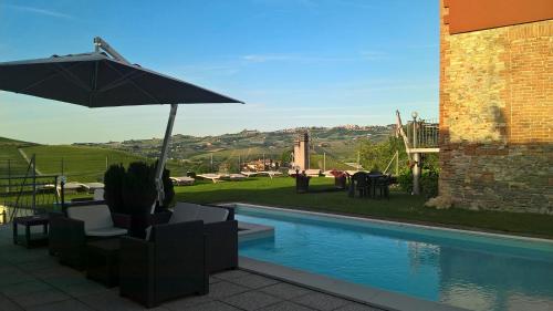 a patio with an umbrella and a swimming pool at Red Wine Camere in La Morra