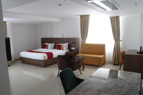 Habitación de hotel con cama y silla en Hotel Seven Lights en Ernakulam