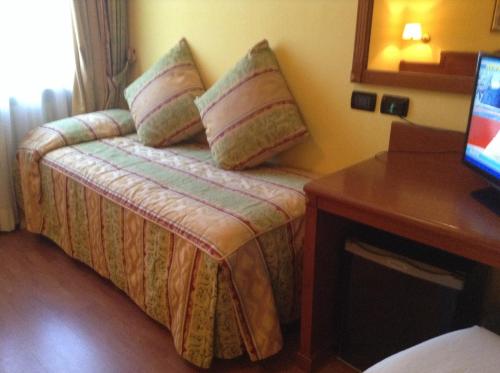 a hotel room with a bed with pillows and a desk at Hotel Cinzia Ristorante Christian e Manuel in Vercelli