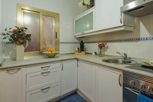 una cocina blanca con fregadero y un bol de fruta en Apartamento de diseño, en Alcalá de Henares