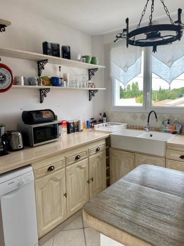 une cuisine avec un évier et un micro-ondes dans l'établissement Appartement Royan Pontaillac Métairie, à Royan