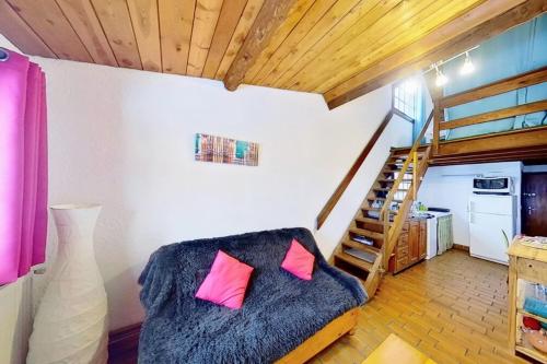 ein Zimmer mit einem Sofa mit rosa Kissen und einer Treppe in der Unterkunft CASA-La Lorraine lovely studio in a chalet St-Véran 4p 