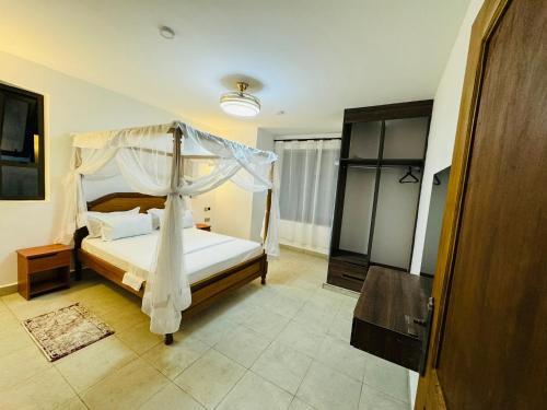 a bedroom with a bed with a canopy at Tulivu Suites Diani in Ukunda