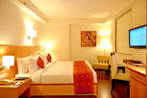 a hotel room with a bed and a desk and a television at The Theme, Jaipur in Jaipur