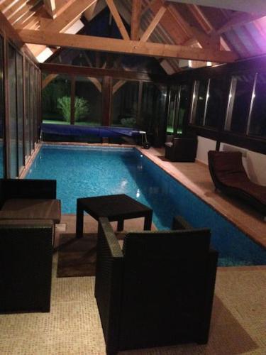 - une grande piscine avec une table et des chaises dans l'établissement DOMAINE DU BOIS L'ABBE, à Épaignes
