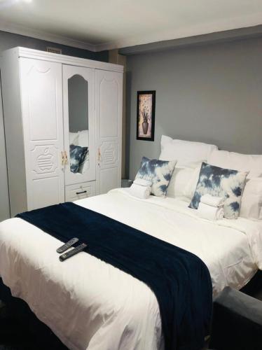 a bedroom with a large white bed with a black blanket at Rose-Lee Cottage in Durban