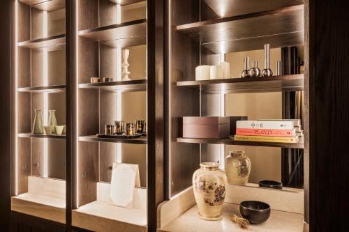 une armoire en bois avec des étagères, des vases et des livres dans l'établissement Hotel Hana, à Paris