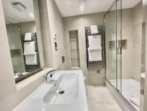a white bathroom with a sink and a shower at Drury Lane Residences in London