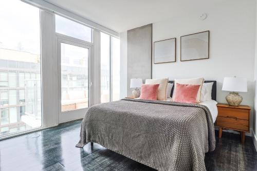 a white bedroom with a bed with pink pillows at Spectacular 3BDR & BTH in DTLA with pool, gym and balcony amazing views in Los Angeles