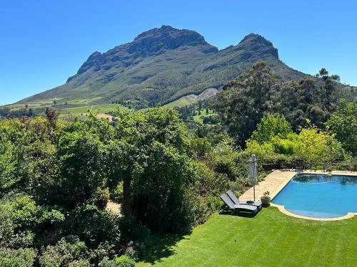 - une piscine dans une cour avec des montagnes en arrière-plan dans l'établissement Camberley Wines - Luxury Accommodation, à Stellenbosch