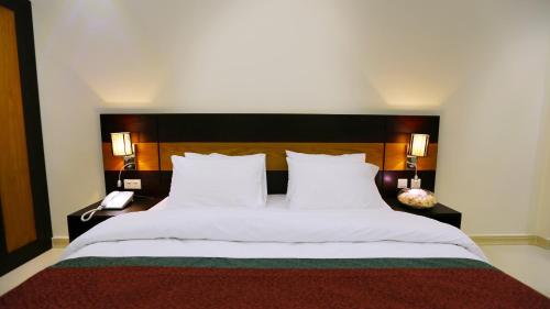 a bedroom with a large bed with white sheets and two lamps at Muscat International Hotel Plaza in Salalah