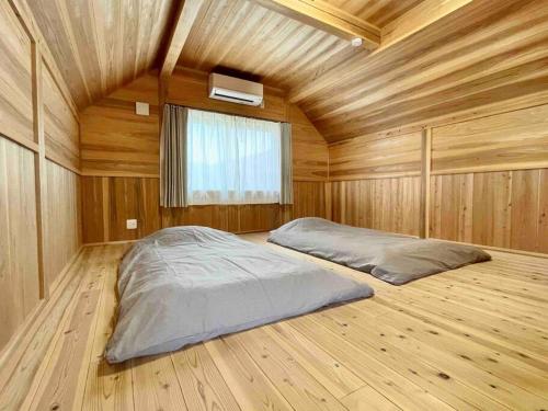 a bedroom with a large bed in a wooden room at 飲食店やスーパーも徒歩圏内！豊かな自然と共存するウッドハウス。 