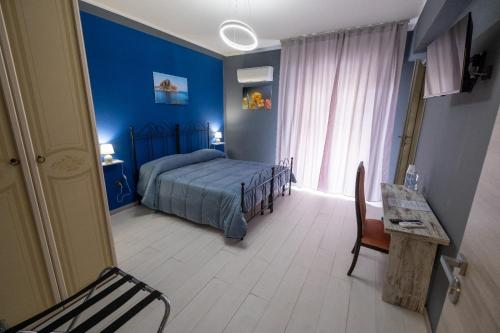 a bedroom with blue walls and a bed and a table at Room 112 Oltremare in Bagheria