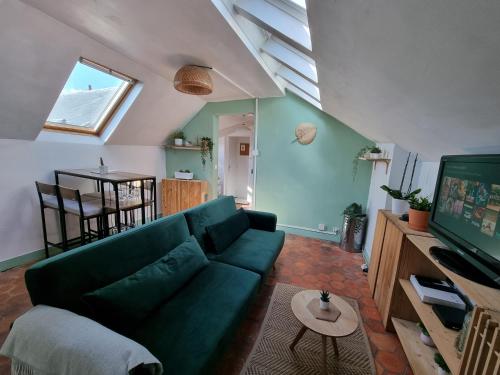 een woonkamer met een groene bank en een tv bij Charmant studio proche du château in Versailles