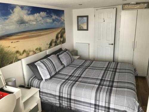 a bedroom with a bed with a painting on the wall at Little Owl Self Catering in Little Barningham